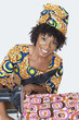 Photo: Portrait of an African American female fashion designer sewing fabric over gray background Portrait of an African American female fashion designer sewing fabric over gray background