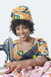 Photo: Portrait of an African American woman using sewing machine over gray background Portrait of an African American woman using sewing machine over gray background