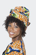 Foto: Portrait of young woman in African print attire looking over shoulder against gray background Portrait of young woman in African print attire looking over shoulder against gray background