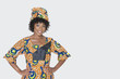 Foto: Portrait of young woman in African print attire standing with hands on hips over gray background Portrait of young woman in African print attire standing with hands on hips over gray background