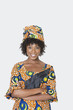 Foto: Portrait of young woman in African print attire standing arms crossed over gray background Portrait of young woman in African print attire standing arms crossed over gray background