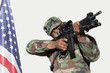 Photo: US Marine Corps soldier aiming M4 assault rifle with American flag against gray background US Marine Corps soldier aiming M4 assault rifle with American flag against gray background
