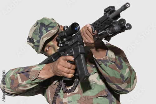 Photo: US Marine Corps soldier aiming M4 assault rifle against gray background US Marine Corps soldier aiming M4 assault rifle against gray background