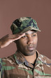 Foto: Close-up of a young African American US Marine Corps soldier saluting over brown background Close-up of a young African American US Marine Corps soldier saluting over brown background