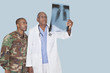 Foto: Senior doctor with US Marine Corps soldier looking at x-ray report over light blue background Senior doctor with US Marine Corps soldier looking at x-ray report over light blue background