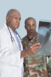 Foto: Senior doctor with US Marine Corps soldier looking at x-ray report over light blue background Senior doctor with US Marine Corps soldier looking at x-ray report over light blue background