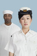 Photo: Portrait of serious female US Navy officer in front male sailor over light blue background Portrait of serious female US Navy officer in front male sailor over light blue background