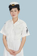 Foto: Portrait of a young female US Navy officer standing with hands clasped over light blue background Portrait of a young female US Navy officer standing with hands clasped over light blue background