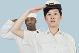 Photo: Portrait of serious female US Navy officer and male sailor saluting over light blue background Portrait of serious female US Navy officer and male sailor saluting over light blue background