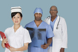 Photo: Portrait of three multi ethnic medical professionals over light blue background Portrait of three multi ethnic medical professionals over light blue background