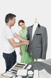 Photo: Male tailor taking measurement of suit while female coworker standing besides Male tailor taking measurement of suit while female coworker standing besides