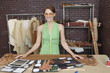 Portrait of pretty female fashion designer standing at table with layouts