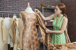 Photo: Young female fashion designer matching cloth with fabric draped on tailor's dummy Young female fashion designer matching cloth with fabric draped on tailor's dummy