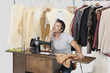 Mature male tailor thinking while sitting at sewing machine with fabric
