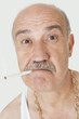 Portrait of senior man with cigarette in mouth over gray background