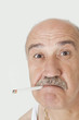 Foto: Portrait of senior man with cigarette in mouth over gray background Portrait of senior man with cigarette in mouth over gray background