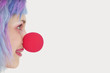 Foto: Profile of woman with red clown nose over gray background Profile of woman with red clown nose over gray background