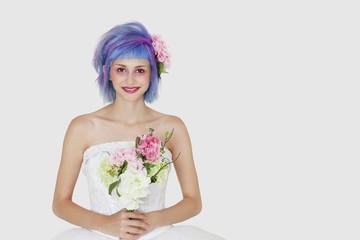 Photo: Portrait of happy young woman in wedding dress with dyed hair against gray background Portrait of happy young woman in wedding dress with dyed hair against gray background