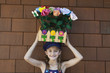 Photo: Portrait of little girl carrying artificial flowers in wooden crate on head Portrait of little girl carrying artificial flowers in wooden crate on head