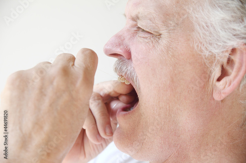 Photo: older man flossing teeth profile view older man flossing teeth profile view