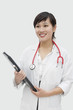 Photo: Young veterinarian holding report with stethoscope around neck over gray background Young veterinarian holding report with stethoscope around neck over gray background