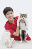 Photo: Portrait of an Asian female veterinarian holding cat against gray background Portrait of an Asian female veterinarian holding cat against gray background