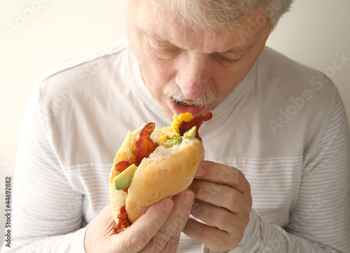 Photo: older man eats bacon, egg and avocado sandwich older man eats bacon, egg and avocado sandwich