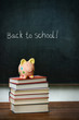 Piggybank and books in front of chalkboard