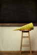 Yellow dunce hat on stool with chalkboard