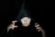 Young wizard - a boy in black cloak on the dark background