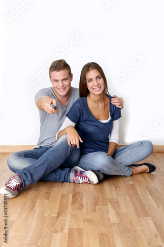 Photo: Cheerful young couple using tv remote control Cheerful young couple using tv remote control