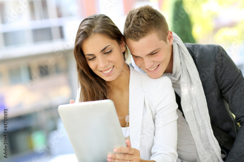 Photo: Trendy young couple in town using tablet Trendy young couple in town using tablet