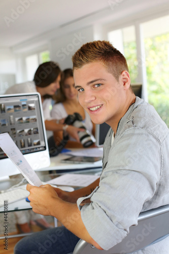Photo: Young man sitting in office in front of desktop computer Young man sitting in office in front of desktop computer