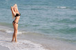 young happy woman in black bikini on sea background