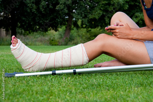 Photo: Girl with leg in plaster chatting with her smartphone Girl with leg in plaster chatting with her smartphone
