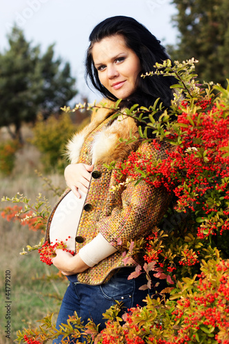 Photo: Portrait of beautiful pregnant woman walking in autumn park Portrait of beautiful pregnant woman walking in autumn park