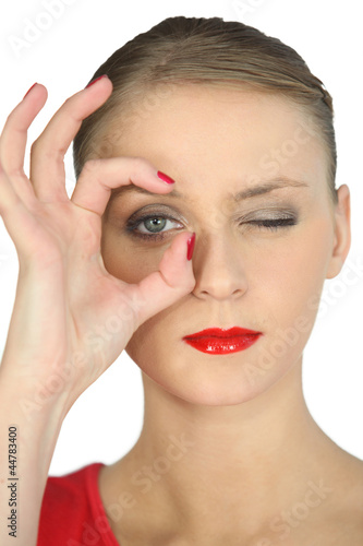 Photo: Woman making a circle with her fingers around her eye Woman making a circle with her fingers around her eye