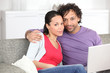 young metis couple doing computer on the couch