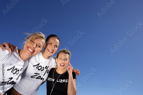 Photo: Three women stood outdoors with headphones Three women stood outdoors with headphones
