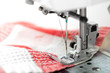 Sewing machine closeup with red fabric on white background
