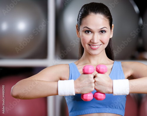 Photo: Athletic woman in sportswear training with dumbbells Athletic woman in sportswear training with dumbbells