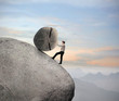 Businessman pushing a boulder on a rock