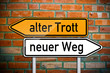 Wegweiser auf Ziegelsteinwand mit alter Trott und neuer Weg
