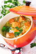 Soup with vegetables and salmon in ceramic pot.