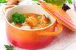 Soup with vegetables and salmon in ceramic pot.