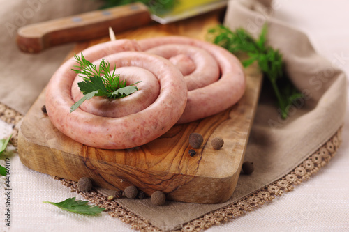 Photo: Raw coiled sausages on wooden board. Raw coiled sausages on wooden board.