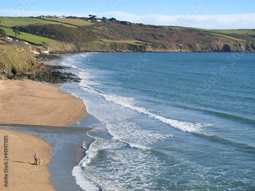 Photo: Woman and dog enjoying beach and ocean at Gerrans Bay, Cornwall, United Kingdom Woman and dog enjoying beach and ocean at Gerrans Bay, Cornwall, United Kingdom