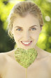 Portrait of young woman holding heart shape leaf on a stick