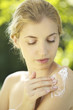 Portrait of young woman putting lotion on shoulder outdoors