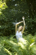 Portrait of young woman stretching among fern leaves outdoors